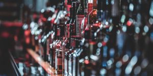 Rows of assorted liquor bottles lined up on a bar counter in low light
