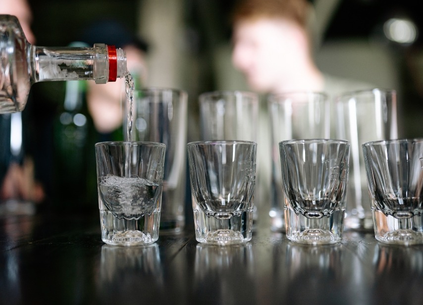 Pouring vodka into shot glasses at a party